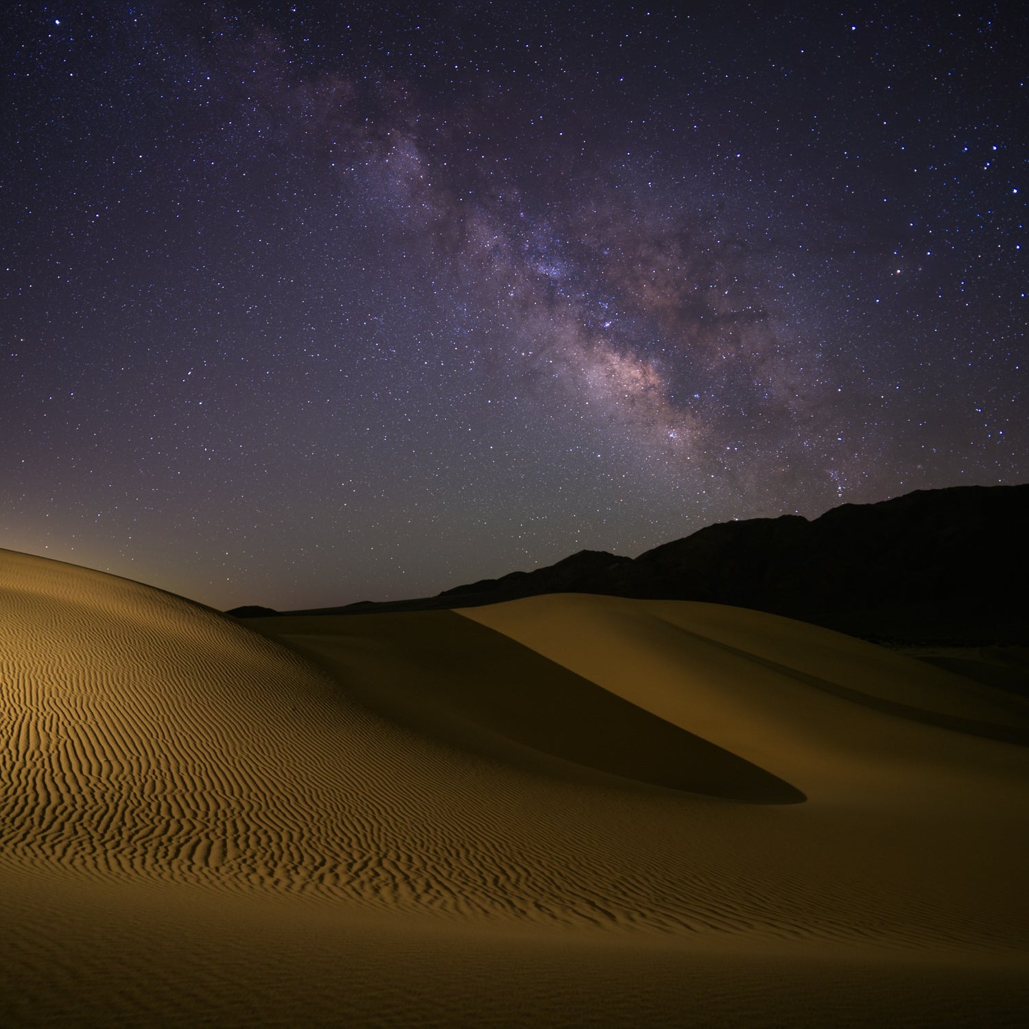 A night photograph of the mesquite sand dunes in Death Valley with the Milky Way visible in the sky.